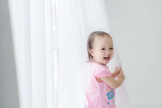 Asian girl holding white curtain at home.